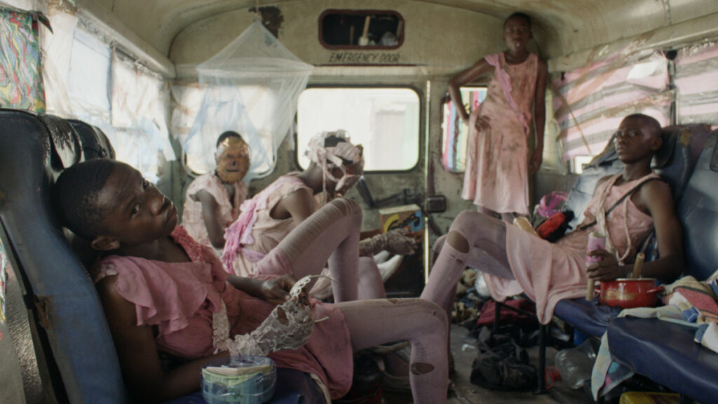 Five people dressed in pink outfits in an old schoolbus